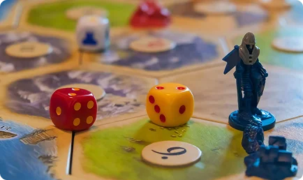 Een close-up van de dobbelstenen en de fiches van spelers op een kleurrijk strategisch bordspel.